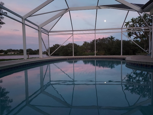 pool at dusk featuring a lanai and an outdoor pool