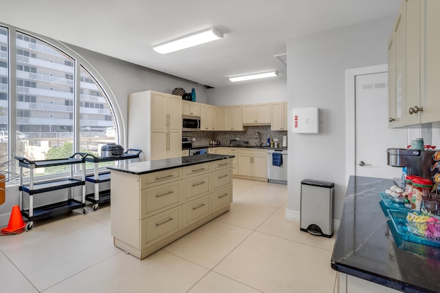 1180 S Ocean Blvd Unit 11D, Boca Raton, FL 33432 - kitchen with stainless steel appliances, dark countertops, backsplash, a sink, and light tile patterned floors