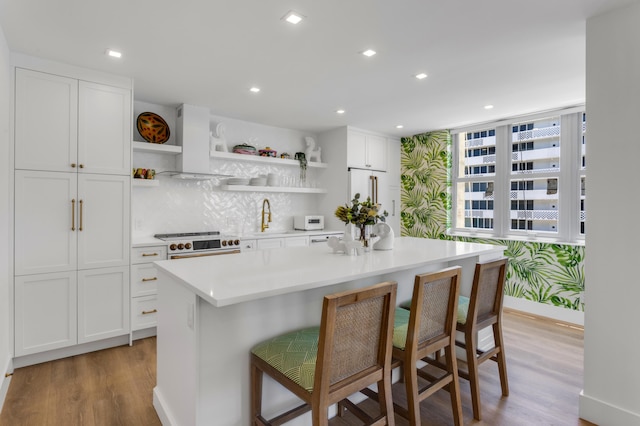 1180 S Ocean Blvd Unit 11D, Boca Raton, FL 33432 - kitchen featuring open shelves, wall chimney range hood, white appliances, light wood-style floors, and white cabinetry