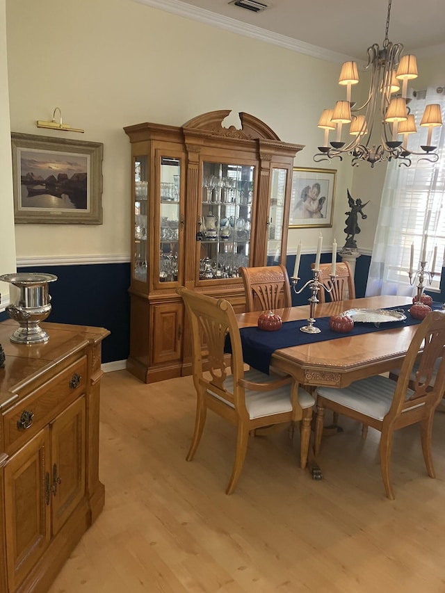 dining space with ornamental molding, a chandelier, and light wood-style flooring