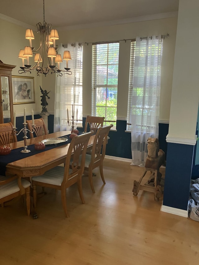dining area featuring ornamental molding, wood finished floors, baseboards, and a chandelier