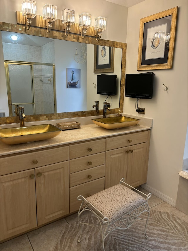 full bathroom featuring a stall shower, tile patterned floors, double vanity, baseboards, and a chandelier