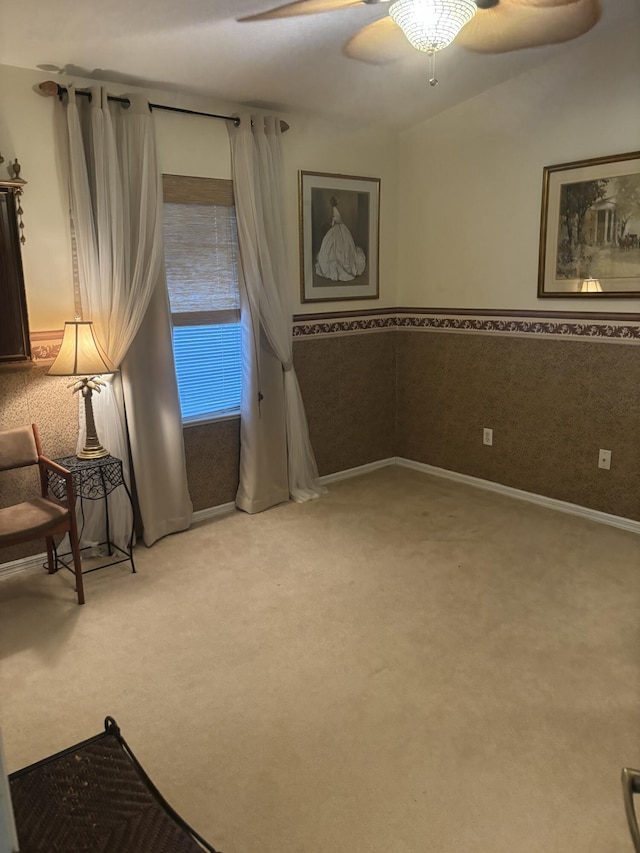 unfurnished room with light carpet, ceiling fan, and a wainscoted wall