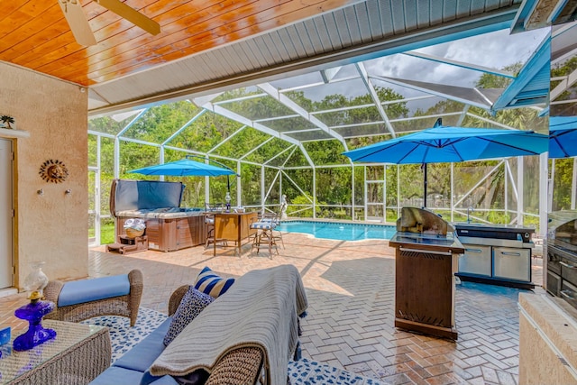 swimming pool with a patio, glass enclosure, exterior kitchen, ceiling fan, and outdoor lounge area
