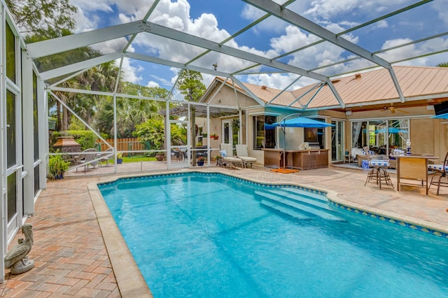 swimming pool with a patio, fence, a lanai, and exterior kitchen
