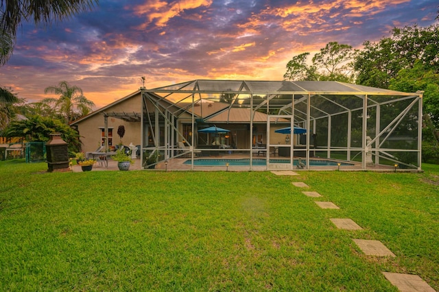 back of property with an outdoor pool, a lawn, a patio area, and a lanai