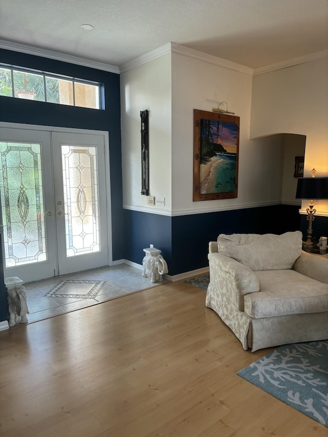 foyer with wood finished floors, french doors, crown molding, and baseboards