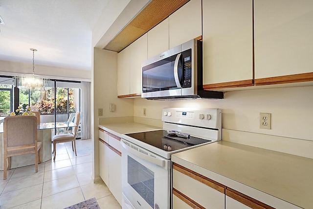 kitchen with light tile patterned floors, a notable chandelier, light countertops, white range with electric cooktop, and stainless steel microwave