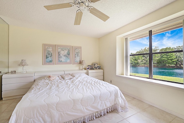 bedroom with a ceiling fan, tile patterned floors, multiple windows, and a textured ceiling