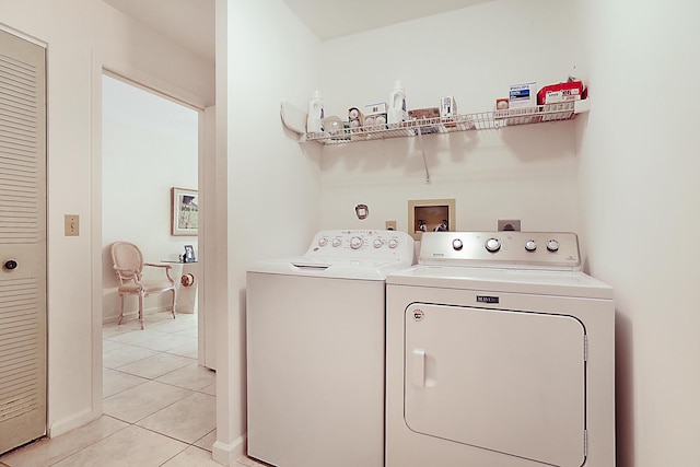washroom with baseboards, washer and dryer, light tile patterned flooring, and laundry area