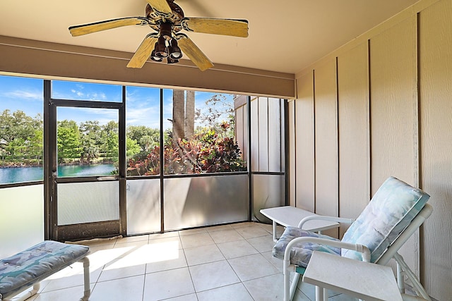 sunroom / solarium with a ceiling fan and a water view