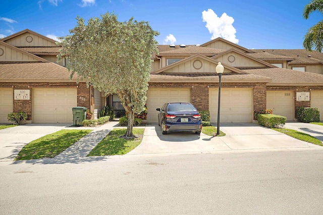 townhome / multi-family property with brick siding, a garage, driveway, and roof with shingles