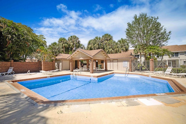 pool with a patio area and fence