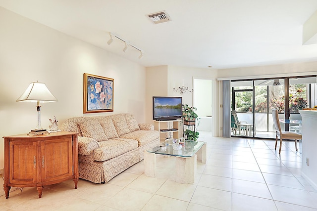 living area with track lighting, light tile patterned floors, and visible vents