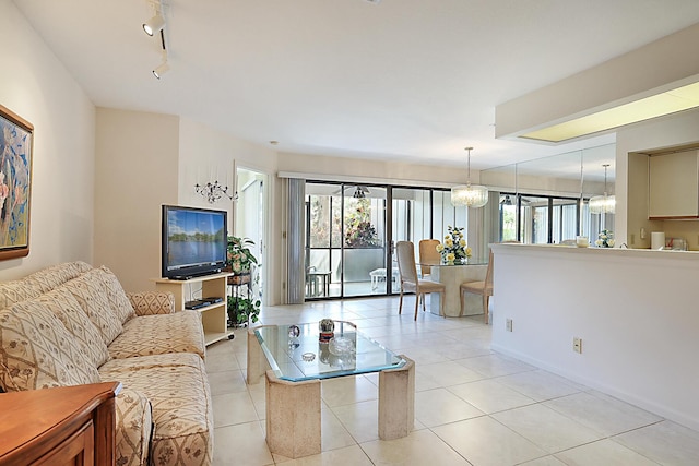 living area with rail lighting, light tile patterned floors, baseboards, and an inviting chandelier