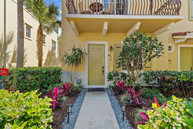 property entrance featuring stucco siding and a balcony