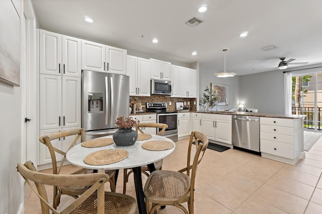 kitchen featuring a peninsula, visible vents, a sink, stainless steel appliances, and backsplash