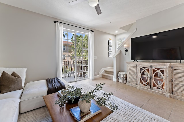 living area with baseboards, tile patterned floors, stairway, a textured ceiling, and ceiling fan