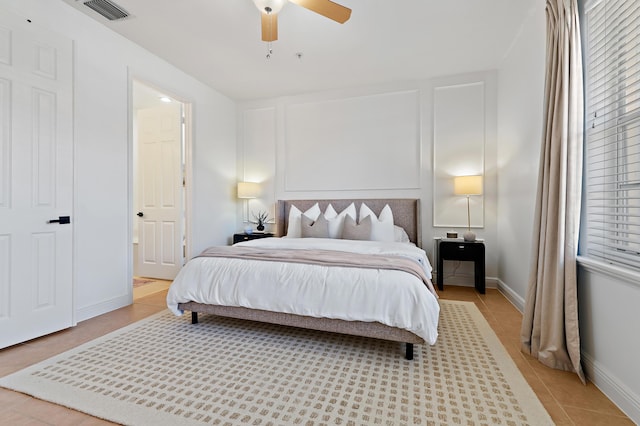 bedroom featuring light tile patterned floors, visible vents, baseboards, and ceiling fan