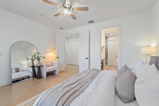 bedroom with light tile patterned floors, visible vents, baseboards, and ensuite bath