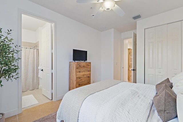 bedroom with visible vents, a closet, light tile patterned floors, ceiling fan, and ensuite bath