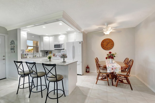 815 Club Dr Unit D, Delray Beach, FL 33445 - kitchen featuring white appliances, a kitchen breakfast bar, a kitchen island, light stone counters, and white cabinetry