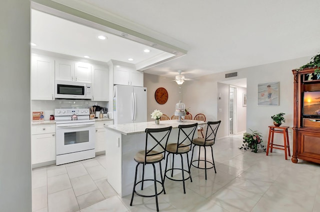 815 Club Dr Unit D, Delray Beach, FL 33445 - kitchen featuring white appliances, a breakfast bar, a kitchen island, white cabinetry, and recessed lighting