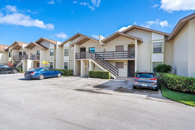 1811 SW Palm City Rd Unit A-202, Stuart, FL 34994 - view of front facade featuring stairs, uncovered parking, a residential view, and stucco siding