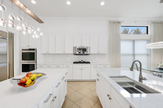 kitchen with stainless steel appliances, a sink, light tile patterned floors, backsplash, and decorative light fixtures