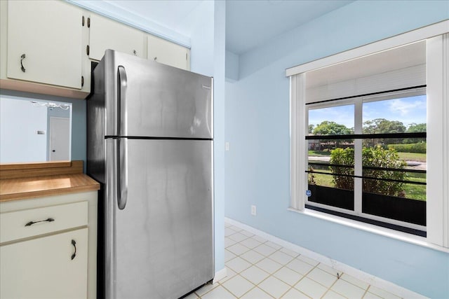 6117 Woodlake Blvd, Greenacres, FL 33463 - kitchen with freestanding refrigerator, white cabinetry, light tile patterned floors, and baseboards