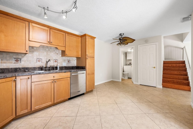kitchen featuring dark countertops, visible vents, decorative backsplash, dishwasher, and a sink