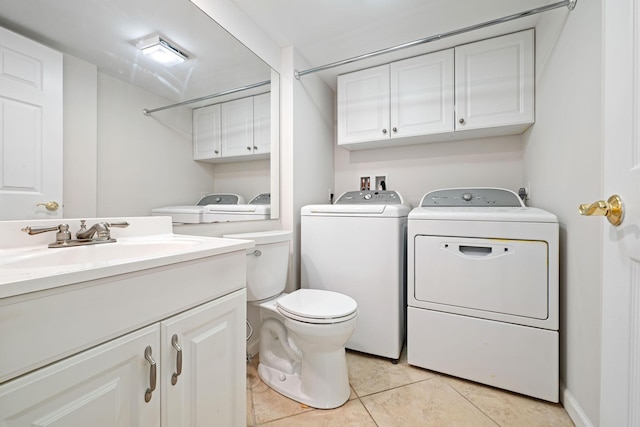 washroom with light tile patterned floors, washing machine and dryer, laundry area, and a sink