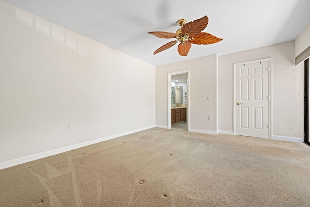 unfurnished bedroom featuring baseboards, light colored carpet, connected bathroom, and ceiling fan