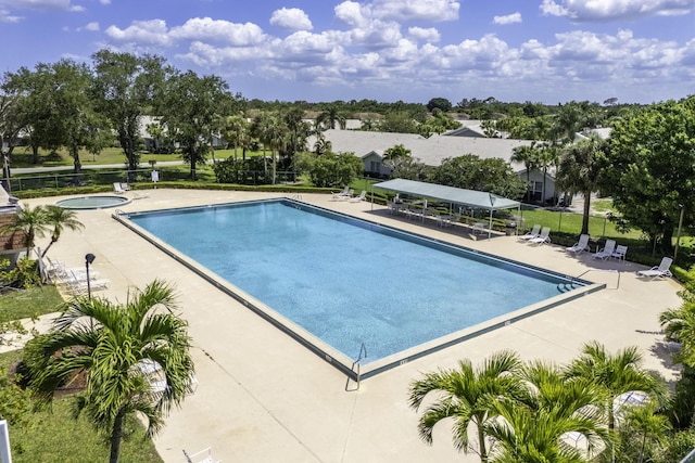 community pool with a patio, fence, and a hot tub