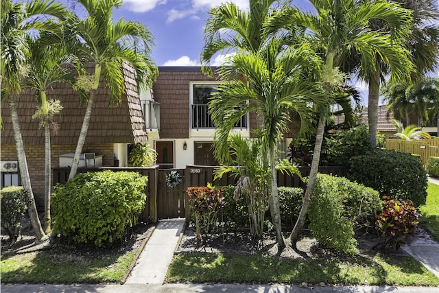exterior space featuring brick siding, mansard roof, and a fenced front yard