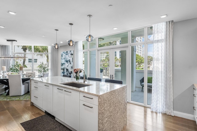 3200 S Ocean Blvd Unit 101, Highland Beach, FL 33487 - kitchen featuring a sink, hardwood / wood-style flooring, white cabinetry, hanging light fixtures, and a wall of windows