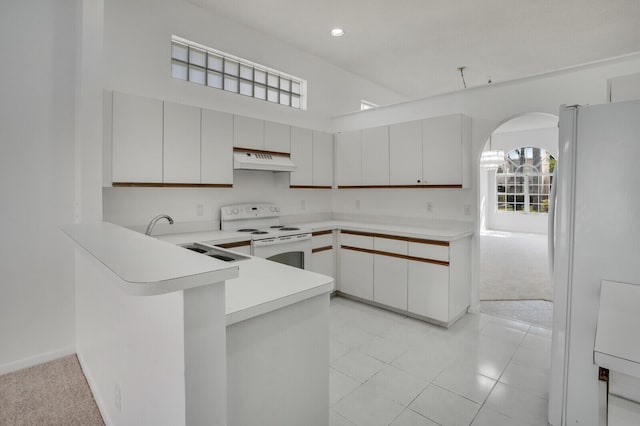 kitchen with white appliances, a peninsula, light carpet, under cabinet range hood, and light countertops