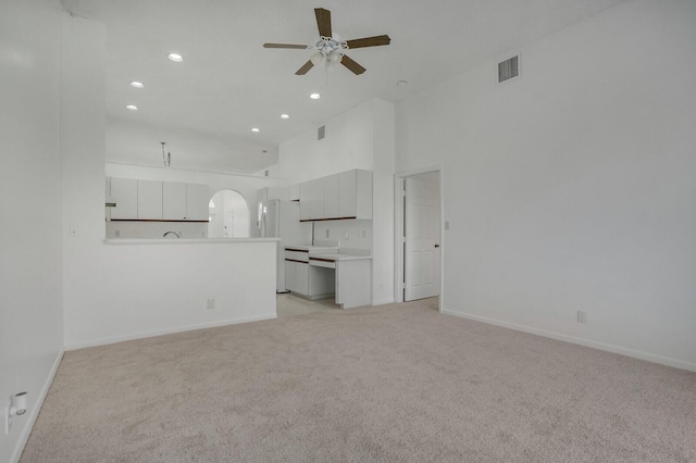 unfurnished living room with arched walkways, a ceiling fan, visible vents, recessed lighting, and light carpet