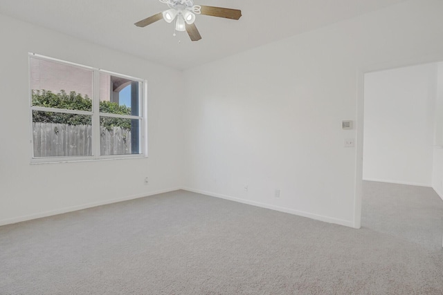 carpeted empty room featuring baseboards and a ceiling fan