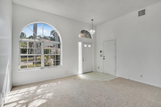 foyer with a notable chandelier, visible vents, and carpet floors