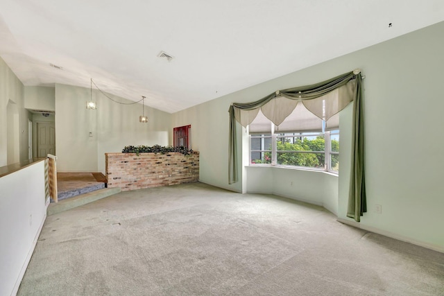carpeted spare room with visible vents and vaulted ceiling