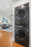 clothes washing area with stacked washer / drying machine and wood finished floors