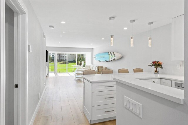 kitchen featuring recessed lighting, open floor plan, light wood-style flooring, light countertops, and white cabinetry