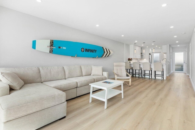 living room with recessed lighting, light wood-style flooring, and baseboards