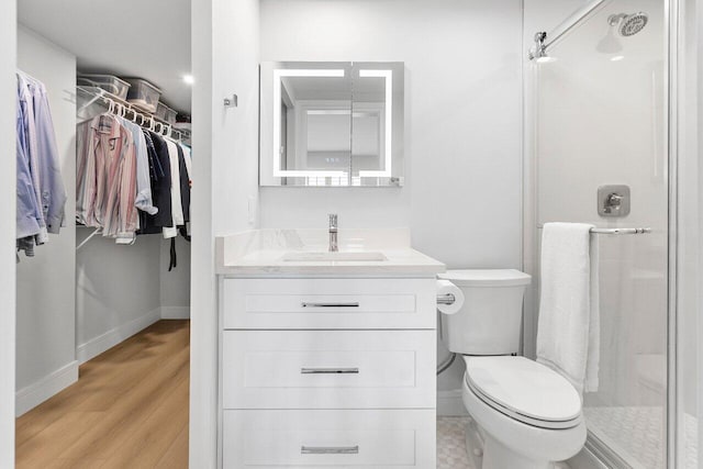 full bathroom with toilet, a stall shower, wood finished floors, and baseboards