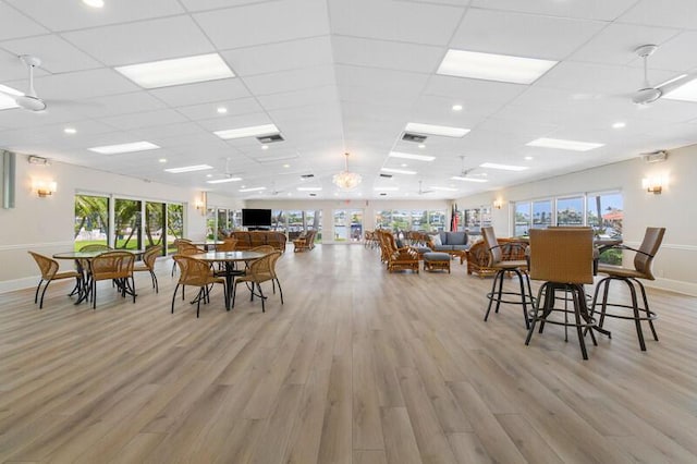dining area featuring light wood-type flooring, a paneled ceiling, and baseboards
