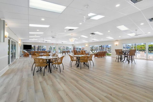 dining space featuring a paneled ceiling, light wood-style flooring, visible vents, and a ceiling fan