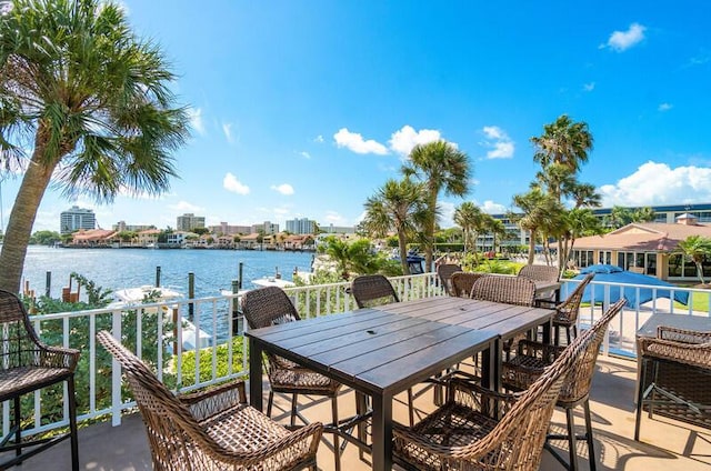 view of patio featuring a water view, outdoor dining area, and a balcony