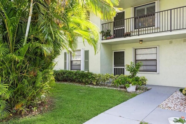 701 Sabal Ridge Cir Unit C, Palm Beach Gardens, FL 33418 - doorway to property featuring stucco siding, a balcony, and a lawn
