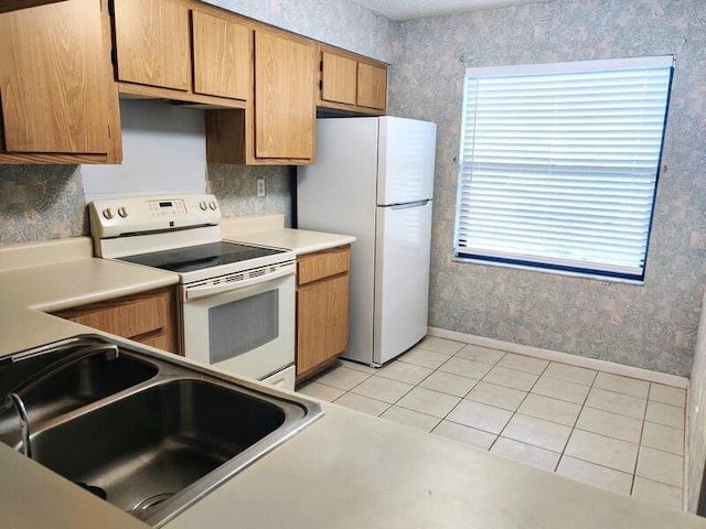 701 Sabal Ridge Cir Unit C, Palm Beach Gardens, FL 33418 - kitchen featuring white appliances, a sink, wallpapered walls, light tile patterned flooring, and baseboards